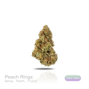 PUFFY Peach Ringz is an indica-dominant hybrid THCa strain born from the flavorful cross of Marionberry and Eddy OG. The aroma bursts with gassy, sweet, and fruity notes, creating an enticing and vibrant sensory experience. Visually, the buds are bushy and densely packed, covered in glistening trichomes with minty  green tones and dark olive undertones. Consumers frequently describe this strain as offering a harmonious experience, starting with a light, uplifting mental clarity that brightens the mood, foll