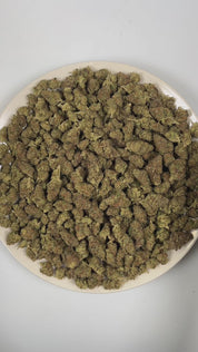 PUFFY Glitter Bomb is an indica-dominant hybrid THCa strain born from the flavorful cross of Grape Gas #10 and OGKB Blueberry Headband. The aroma is a vibrant blend of fruity sweetness, layered with gassy undertones and a refreshing hint of tropical notes. Visually, the buds are dense and deep forest green with striking purple hues, bright orange pistils, and a heavy coating of sparkling white trichomes. Consumers report a bright rush of cerebral uplift that gently settles into a soothing, full-body calm, l