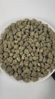 PUFFY Frosted Donut is an indica-dominant  hybrid THCa strain, expertly crafted from a potent cross between Girl Scout Cookies and Louis XIII. The aroma is a delightful blend of sweet berry, smooth vanilla, and fresh pine, creating a rich and inviting fragrance. Visually, the dense buds display bright green and deep purple hues, dotted with orange pistils and coated in sparkling trichomes. Consumers often report an initial euphoric and uplifting cerebral buzz that elevates mood, gradually transitioning into