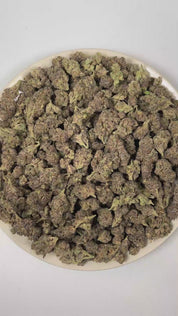 PUFFY Glitter Bomb is an indica-dominant hybrid THCa strain born from the flavorful cross of Grape Gas #10 and OGKB Blueberry Headband. The aroma unfolds with a vibrant burst of ripe berries layered over bright, zesty citrus notes, rounded out by a deep, gassy undertone. Visually, the buds are dense and deep forest green with striking purple hues, bright orange pistils, and a heavy coating of sparkling white trichomes. Consumers report a bright rush of cerebral uplift that gently settles into a soothing, fu