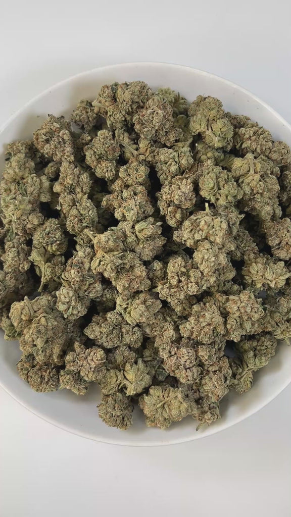 PUFFY Marathon OG is a potent indica-dominant hybrid THCa strain, crafted from the legendary OG Kush lineage, which includes either Chemdawg, Lemon Thai, or Hindu Kush. The aroma is bold and layered, combining gassy sharpness with earthy depth and a touch of warm spice. Visually, the buds are dense and deep forest green, accented by darker undertones, vivid bright orange pistils, and a thick coating of frosty white trichomes, signaling its high potency. Consumers often report a balance of euphoria and relax