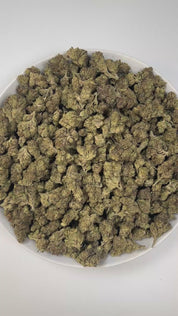 PUFFY Carbon Fiber is a balanced hybrid THCa strain, created from a potent blend of Grape Pie, Biscotti, and Cookies & Cream. The aroma blends creamy sweetness with sharp chemical tones and a grounding woody finish, resulting in a bold and complex scent profile. Visually, the buds are dense and striking, featuring deep green and purple hues, coated in frosty trichomes and accented with bright orange pistils. Consumers often describe the smoke as creamy and smooth, with a powerful high that feels giggly, tin