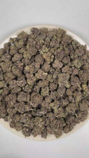 PUFFY Gruntz is an indica-dominant hybrid THCa strain born from the distinguished cross of Original Z and Gelato. The aroma opens with a bold grape-forward sweetness layered over sugary candy notes, while a deep gassy undertone adds a pungent, fuel-like edge. Visually, dense deep forest green buds with purple hues and fiery orange pistils are coated in sticky trichomes. Consumers often report a euphoric and uplifting mental state with improved focus, accompanied by a deep sense of calm and a soothing body r