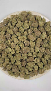 PUFFY Blueberry Pancake is an indica-dominant hybrid THCa strain born from the cross of DJ Short Blueberry and either Purple Panty Dropper or a hybrid with Slurricane. The aroma features luscious blueberry notes layered with sugary sweetness and a nostalgic candy-like finish. Visually, the buds are dense and heavily coated in trichomes, displaying a vibrant mix of deep green, blue-purple, and olive tones, accented by bright orange pistils and a thick layer of visible resin. Consumers often report a soothing