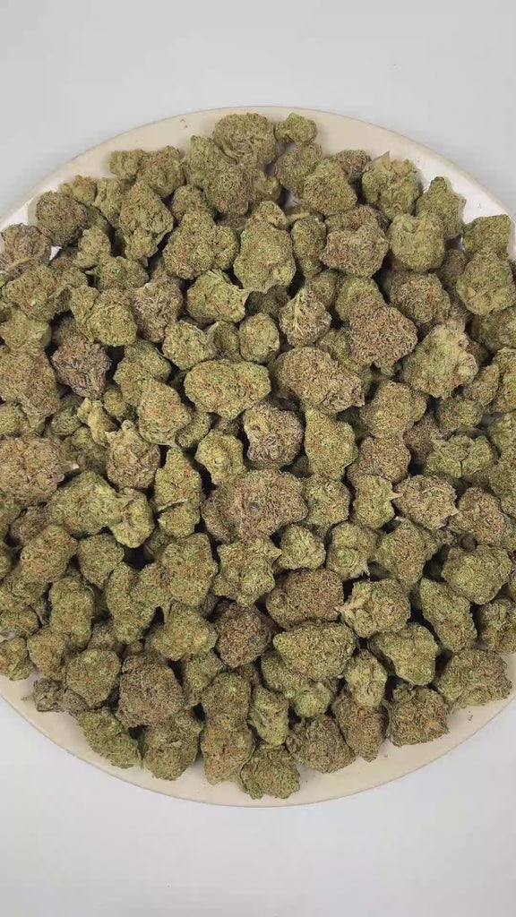 PUFFY Blueberry Pancake is an indica-dominant hybrid THCa strain born from the cross of DJ Short Blueberry and either Purple Panty Dropper or a hybrid with Slurricane. The aroma features luscious blueberry notes layered with sugary sweetness and a nostalgic candy-like finish. Visually, the buds are dense and heavily coated in trichomes, displaying a vibrant mix of deep green, blue-purple, and olive tones, accented by bright orange pistils and a thick layer of visible resin. Consumers often report a soothing