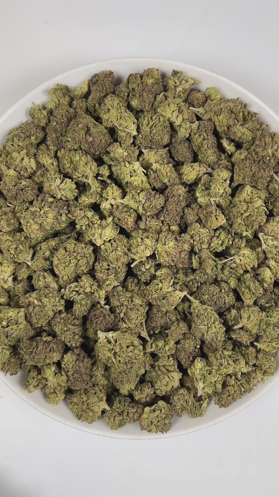 PUFFY Wedding Crasher is a balanced hybrid THCa strain, born from the flavorful union of Wedding Cake × Purple Punch. The aroma is a captivating blend of herbal, smoky, and gassy notes, creating a rich and distinctive scent profile. Visually, the buds are tightly formed, displaying green and purple hues highlighted by bright orange pistils and a thick coating of sparkling trichomes that create a frosty finish. Consumers often report feeling euphoric, focused, and deeply relaxed, accompanied by a happy, upli