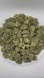 PUFFY GMO, also known as Garlic Cookies, is an indica-dominant hybrid THCa strain crafted from the legendary lineage of Girl Scout Cookies and Chemdawg. The aroma is rich with savory notes of onion and garlic, finishing with a distinctly savory character. Visually, dense deep forest green buds with purple hues and fiery orange pistils are coated in sticky trichomes. Consumers often report euphoric and uplifting mental effects that elevate mood and promote a positive mindset, followed by deep physical relaxa